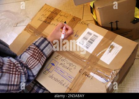 Hamburg, Deutschland. 07. Februar 2023. Eine Frau kennzeichnet einen Karton als Teil einer privaten Spendenaktion in einer geschlossenen Bar in Hamburg-Altona. Nach dem schweren Erdbeben im türkisch-syrischen Grenzgebiet werden Hilfslieferungen mit Gegenständen wie Kleidung, Decken, Babyprodukten und Hygieneartikeln gesammelt und in die Türkei geschickt. Kredit: Bodo Marks/Bodo Marks/dpa/Alamy Live News Stockfoto