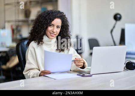 Junge lateinische Geschäftsfrau mit Dokumenten im Amt. Stockfoto