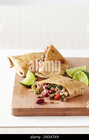 Bohnenburrito gefüllt mit Hackfleisch, Paprika und Salat, auf Holzbrett Stockfoto