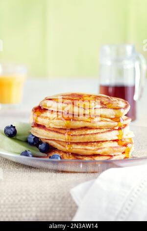 Stapel Buttermilch-Pfannkuchen mit Blaubeeren und Honigmelone garniert mit Ahornsirup Stockfoto