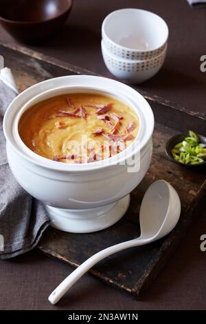 Erbsensuppe mit Schinken in einer Servierschale mit Kelle Stockfoto