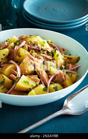 Kartoffelsalat mit Thunfisch, Kapern und violetten Zwiebeln auf blaugrünem Hintergrund Stockfoto