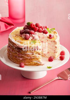 Himbeerkuchen auf einem Podest-Kuchenständer auf pinkfarbenem Hintergrund Stockfoto