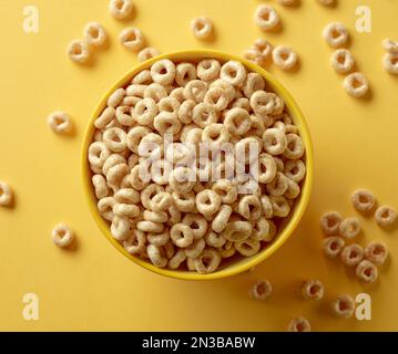 Schale mit Frühstückszerealien Honigringen isoliert auf gelbem Hintergrund, Draufsicht Stockfoto
