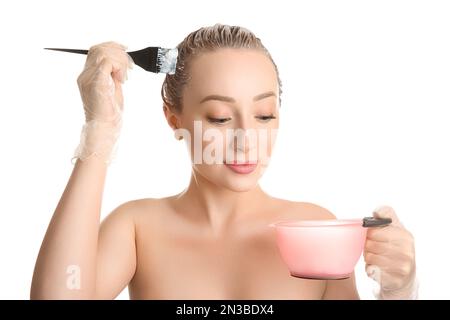 Junge Frau, die Haare vor weißem Hintergrund färbt Stockfoto