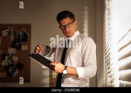 Ein Detective mit Klemmbrett, der in seinem Büro arbeitet Stockfoto