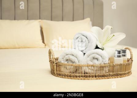 Gerollte saubere Handtücher und Shampooflaschen auf dem Bett. Platz für Text Stockfoto