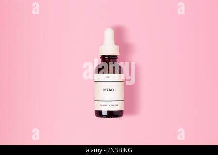 Retinol in einem glasbraunen Kosmetikgefäß. Mit einer Inschrift. Auf pinkfarbenem Hintergrund. Stockfoto