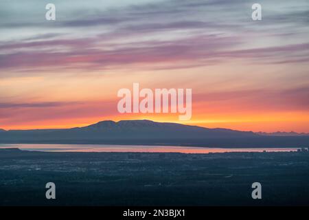 Die Sonne untergeht über dem Mt. Susitna oder Sleeping Lady, gegenüber Cook Inlet von Downtown Anchorage, Alaska auf Dena’ina Land, mit Blick auf Knik Arm Stockfoto