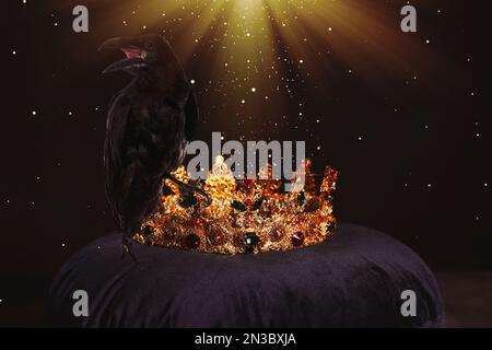 Fantasiewelt. Schwarze Krähe, beleuchtet von magischem Licht, das auf der goldenen Krone sitzt Stockfoto