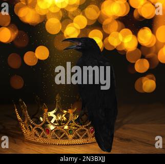Fantasiewelt. Schwarze Krähe auf goldener Krone, Bokeh-Effekt Stockfoto
