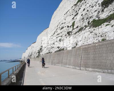 Menschen radeln entlang der weißen Kreidefelsen Promenade mit Meer; Brighton, East Sussex, England, Großbritannien Stockfoto