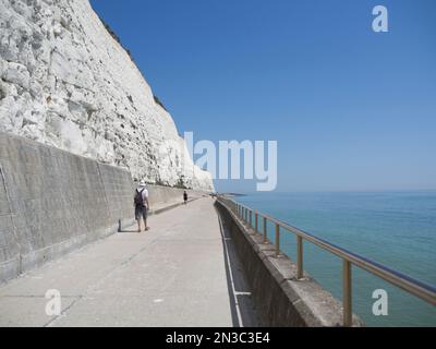 Menschen, die entlang der weißen Kreidefelsen mit Meer spazieren; Brighton, East Sussex, England, Vereinigtes Königreich Stockfoto