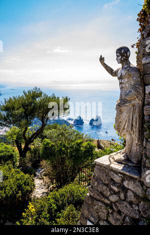 Statue des römischen Kaisers Tiberius mit Blick auf die Bucht von Faraglioni und Felsformationen vom Monte Solaro auf der Insel Capri; Neapel, Capri, Italien Stockfoto