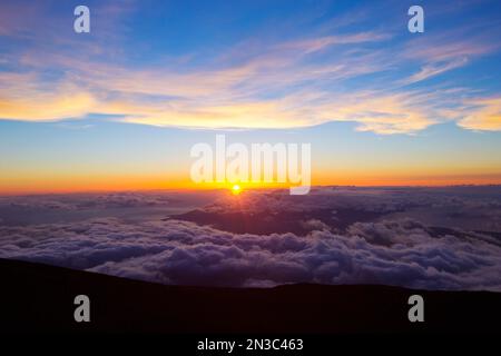 Magischer Sonnenuntergang über den Wolken auf Haleakala; Upcountry Maui, Maui, Hawaii, Vereinigte Staaten von Amerika Stockfoto