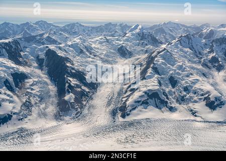 Blick aus der Vogelperspektive auf den blauen Himmel über die atemberaubende Landschaft des Kluane National Park mit den schneebedeckten Berggipfeln und Gletschern, die das Land ausmachen... Stockfoto