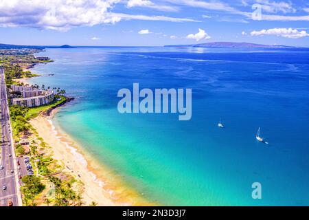 Hotel am Meer und Küstenstraße entlang des Sandstrands von Kamaole Beach I in Kihei mit Segelbooten vor der Küste und Blick auf Hawaii ist... Stockfoto