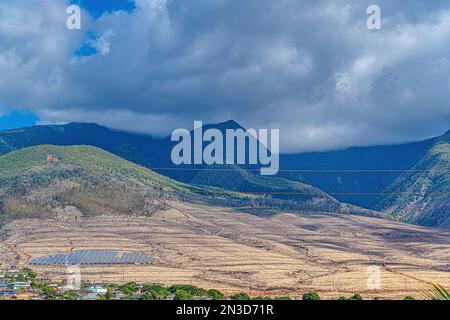 Sonnenkollektoren und Stromleitungen am Berghang über den Dächern von Lahaina Town unter stürmischem Himmel; Maui, Hawaii, USA Stockfoto