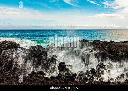 Nahaufnahme des verschwommenen Ozeannebels von den Wellen, die an den Lavafelsen entlang der Küste des Pazifischen Ozeans krachen Stockfoto