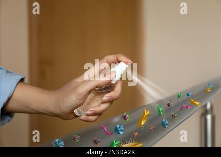 Frau, die Antiseptikum auf Metallgeländer sprüht, voller Mikroben, drinnen, Nahaufnahme Stockfoto