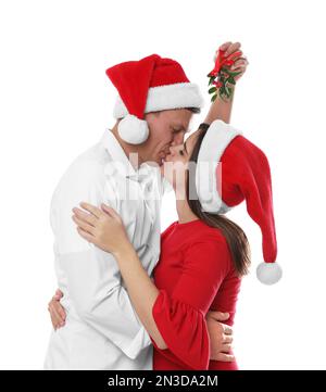 Ein glückliches Paar küsst sich unter Mistelzweigen auf weißem Hintergrund Stockfoto