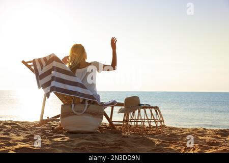 Eine Frau, die sich auf einem Liegestuhl am Sandstrand entspannt. Sommerferien Stockfoto