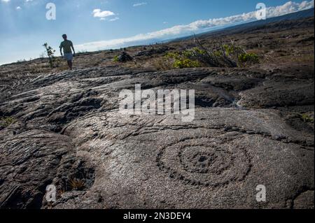 Touristen erkunden die PuIIuloa Petroglyphen, die sich an der Südflanke des Vulkans Kīlauea auf der Big Island von Hawaii befinden, ist PuIIuloa der Name der... Stockfoto