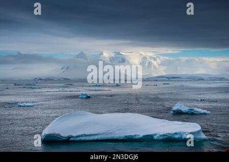 Eisberge im Lemaire-Kanal mit schneebedeckten Gipfeln in der Ferne; Antarktis Stockfoto