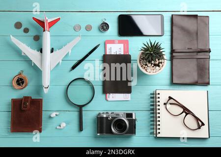 Flach liegend mit Spielzeugflugzeug und Reisegegenständen auf hellblauem Holzhintergrund Stockfoto