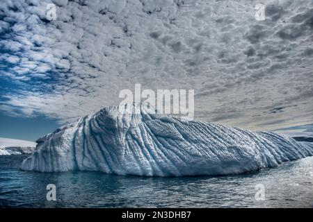 Hohe Wolken über einem Eisberg vor der Enterprise-Insel der Antarktis; Antarktis Stockfoto