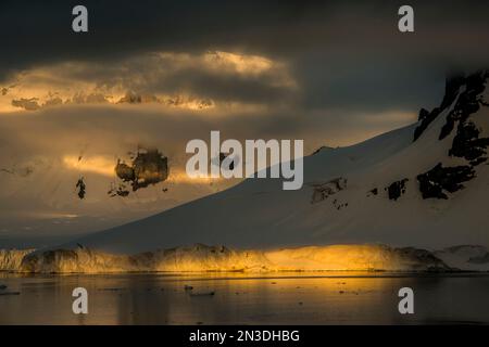 Dramatisches Licht am frühen Morgen beleuchtet die Antarktis Darco Island; Antarktis Stockfoto