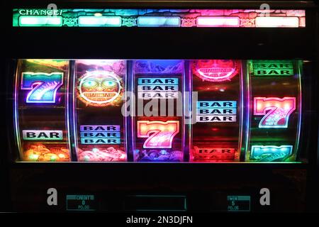 Ein farbenfrohes beleuchtetes Slot Machine-Display, auf dem Siege und verfügbares Guthaben unter den farbenfrohen Trommelrollen mit Themengrafiken angezeigt werden. Stockfoto