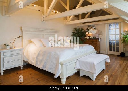 King Size antikes Holzbett im geräumigen Hauptschlafzimmer im Dachgeschoss in einem alten um 1840 Haus. Stockfoto