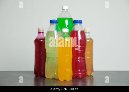 Flaschen mit alkoholfreien Getränken auf dem Tisch vor grauem Hintergrund Stockfoto