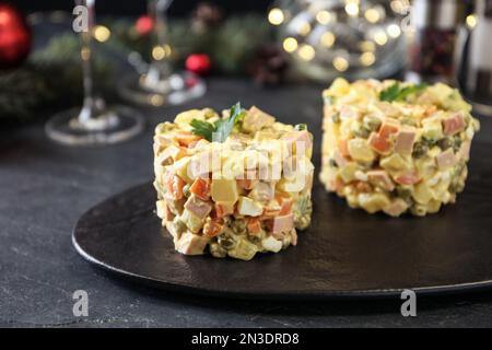 Traditioneller russischer Salat Olivier, serviert auf schwarzem Tisch, Nahaufnahme Stockfoto