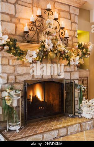 Holzkamin aus Naturstein mit Weihnachtsdekoration im Wohnzimmer im alten renovierten Haus im Canadiana-Cottage-Stil aus dem Jahr 1840. Stockfoto