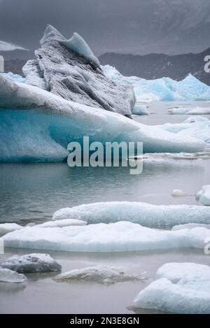 Aus nächster Nähe sehen Sie den Schneefall über Eisbergen entlang des Ufers der Gletscherlagune Jokulsarlon; Vatnajokull-Nationalpark, Island Stockfoto