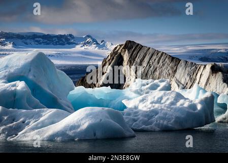 Dramatische Aussicht auf schneebedeckte Landschaft und Eisberge entlang des Ufers der Gletscherlagune Jokulsarlon; Vatnajokull-Nationalpark, Island Stockfoto