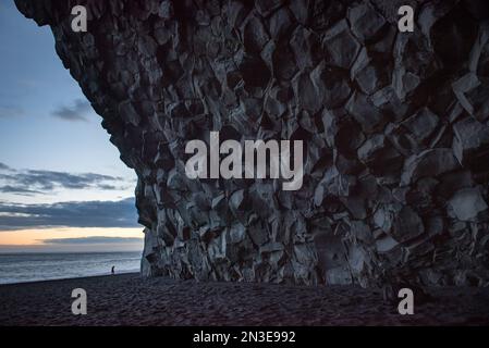 Granithöhle in den Klippen am schwarzen Sandstrand, Reynisfjara Beach, an der Südküste Islands, in der Nähe der Stadt Vik, in der Dämmerung; Island Stockfoto
