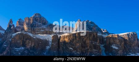 Felsige Gipfel der Sellagruppe, die im Val di Mezdi mit Schnee bedeckt sind, vor einem hellblauen Himmel am Colfosco Corvara in der Bergregion Alta Badia Stockfoto