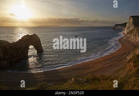 Eine Einzelperson steht am Atlantik neben der Felsformation Durdle Door an der Jurassic Coast bei Lulworth Stockfoto