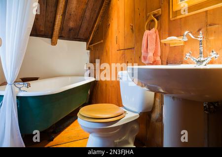 Badezimmer mit grüner, 1880er cm großer Badewanne im oberen Stockwerk im alten, ca. 1750 erbauten Feldsteinhaus im Canadiana-Stil. Stockfoto