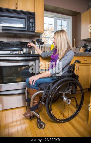 Junge behinderte Frau, die zu Hause in der Küche kocht; Spruce Grove, Alberta, Kanada Stockfoto