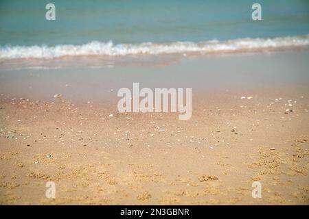 Sand mit verschwommenen Wellen im Hintergrund. Sandstrand, Sommerurlaub. Speicherplatz kopieren. Stockfoto