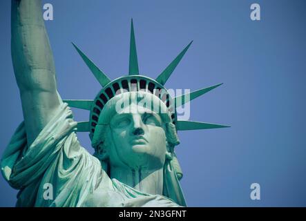 Blick aus der Nähe auf das Gesicht der Freiheitsstatue vor einem hellblauen Himmel an einem sonnigen Tag; New York City, New York, Vereinigte Staaten von Amerika Stockfoto