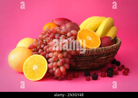 Auswahl an frischen exotischen Früchten und Beeren auf pinkfarbenem Hintergrund Stockfoto