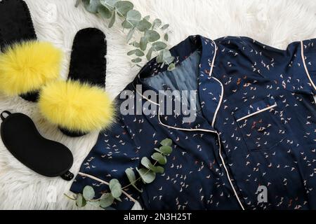 Flach liegend mit flauschigen Hausschuhen und Schlafanzug auf flauschigem Teppich. Bequemes Heim-Outfit Stockfoto