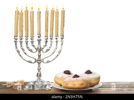 Silberne Menora nahe Sufganiyot und Dreidel mit den Symbolen He, PE, Nun, Gimel auf weißem Hintergrund Stockfoto