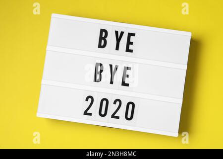 Lichtkästchen mit Text Bye Bye 2020 auf gelbem Hintergrund, Draufsicht Stockfoto