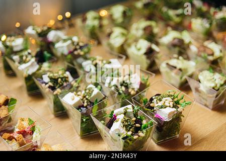 Rübensalat mit Feta-Käsesahne mit Pesto-Sauce und Pinienkernen. Salate in Einweg-Plastiktellern für ein Buffet. Catering bei einer Veranstaltung. Gesundes Papier Stockfoto